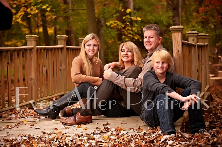 Happy family sitting on bridge.